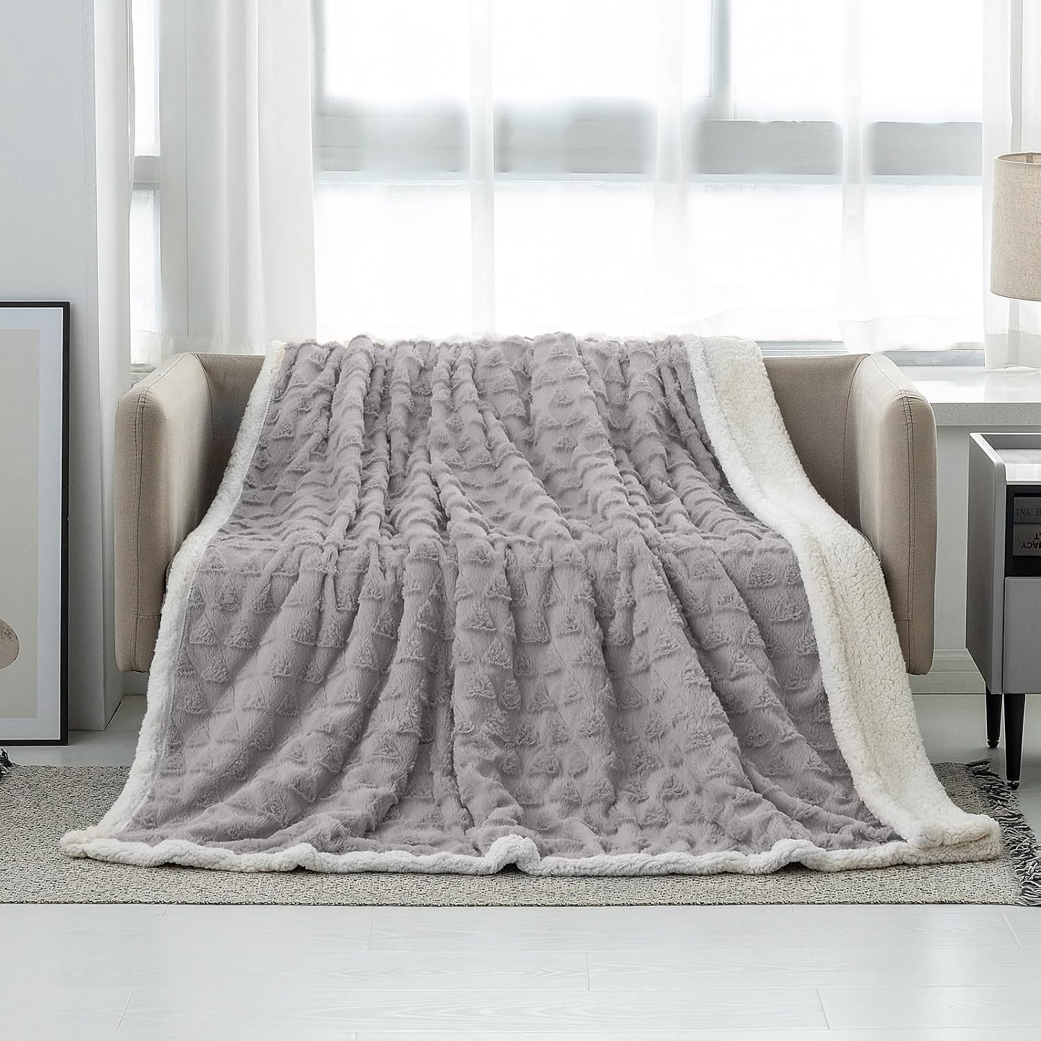 Grey sherpa fleece throw blanket draped over a couch