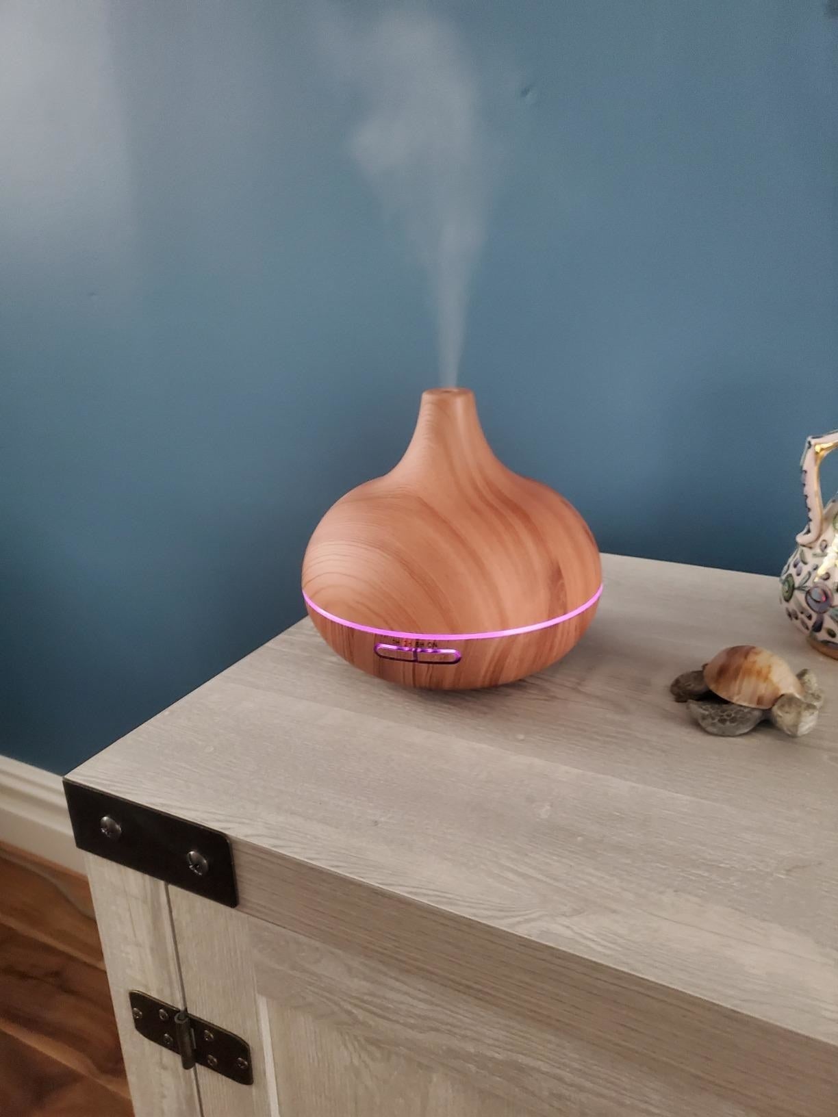 Wood grain teardrop aromatherapy diffuser misting on a table