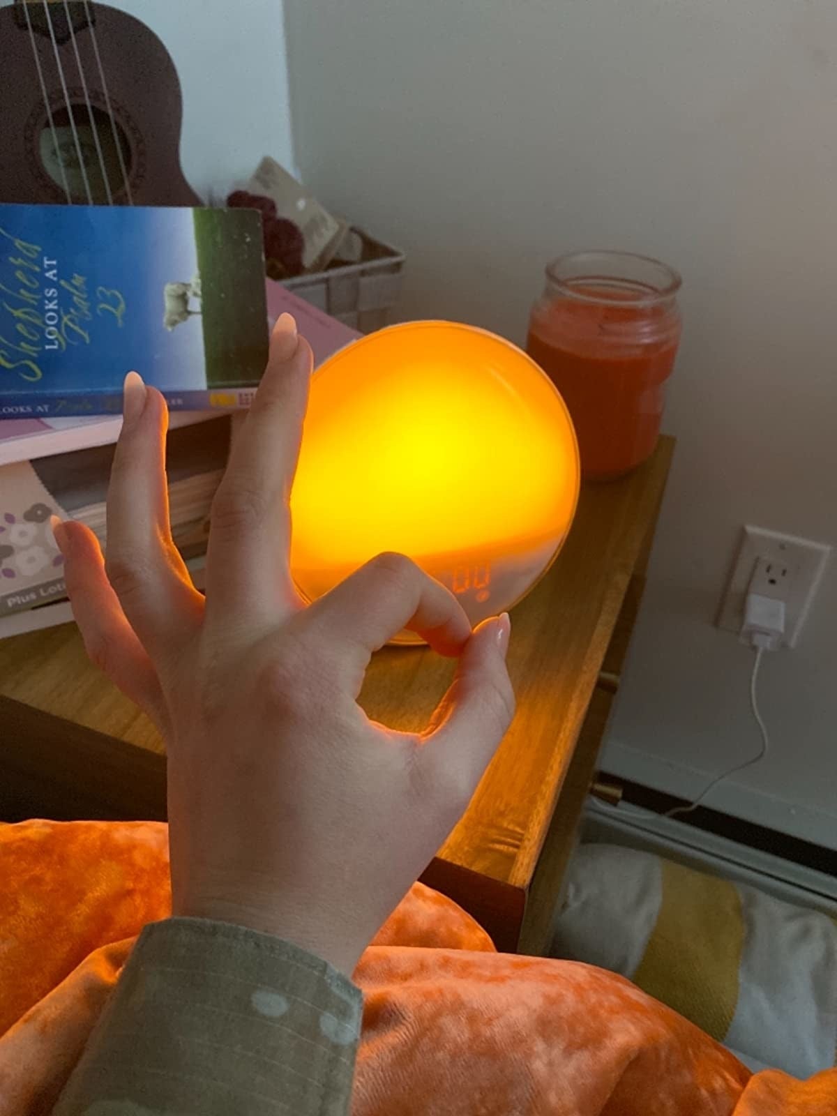 Sunrise alarm clock glowing warm orange on a nightstand